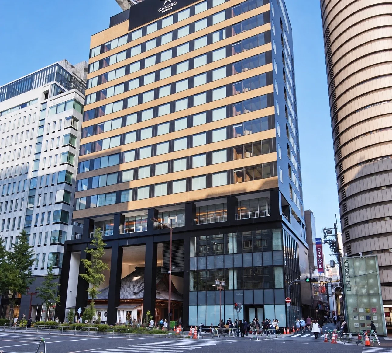 Candeo Hotels Osaka Shinsaibashi seen from the street, with Mitsutera's tiled temple roof visible at ground level